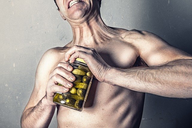 A man struggling to open a jar